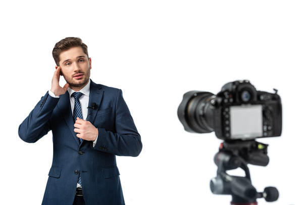 young broadcaster adjusting earphone near digital camera on blurred foreground isolated on white - Photo, Image