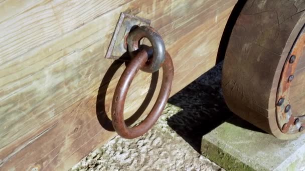 Antique iron knocker on a wooden cracked weathered cannon cart with wooden wheels. Close-up - Πλάνα, βίντεο