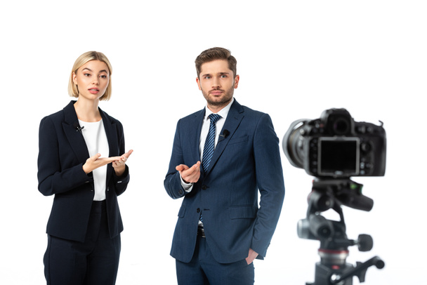 couple of news anchors working near digital camera on blurred foreground isolated on white - Photo, Image