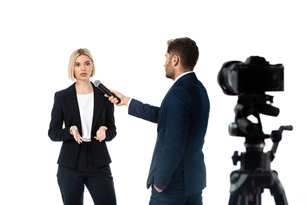 anchorman with hand in pocket taking interview form blonde businesswoman isolated on white, blurred foreground - Photo, Image