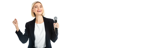 весёлый новостной ведущий с микрофоном, показывающий победный жест изолированный на белом, баннер - Фото, изображение