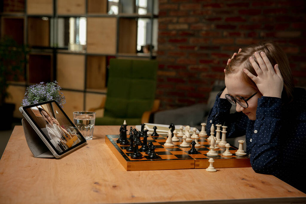 Chytrý malý kavkazský chlapec šachista hrát šachy on-line pomocí notebooku. - Fotografie, Obrázek