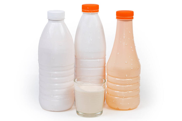 Ферментоване запечене молоко в склянці проти пластикових пляшок різних молочних продуктів на білому фоні, вид збоку
 - Фото, зображення