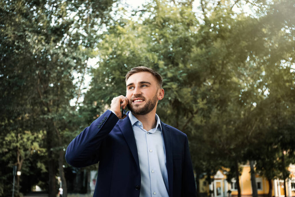 Young man talking on smartphone in park - Fotografie, Obrázek