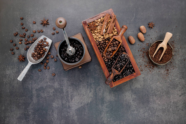Divers grains de café torréfiés dans une boîte en bois avec réglage manuel du moulin à café sur fond de pierre sombre. - Photo, image