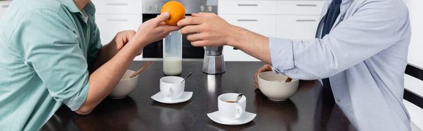 cropped view of homosexual man giving orange to husband during breakfast, banner - Photo, image