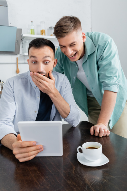 здивована і весела одностатева пара сміється, дивлячись на цифровий планшет
  - Фото, зображення