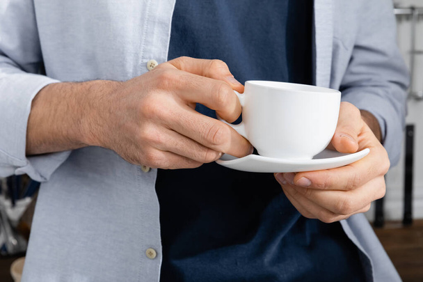 コーヒーとソーサーでカップを握る男の姿が切り取られ ロイヤリティフリー写真 画像素材