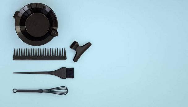 Herramientas de peluquería para teñir el cabello. Accesorios de peluquería en negro sobre fondo azul. Banner con espacio para texto. - Foto, imagen