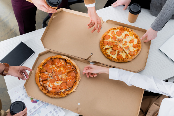 Vágott kilátás üzletemberek vesz pizza ebéd közben az irodában  - Fotó, kép