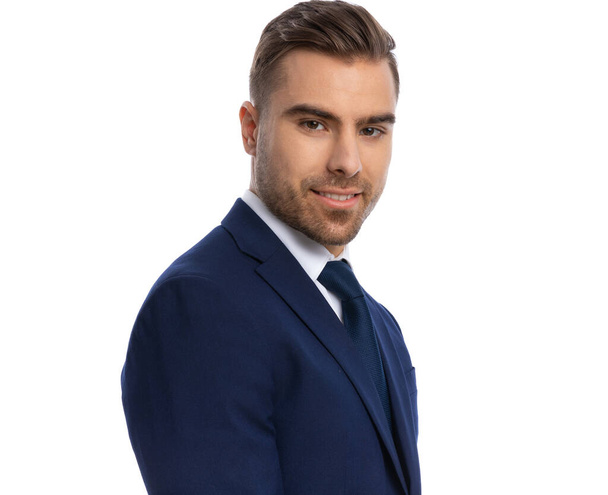 portrait of attractive businessman in navy blue suit smiling and posing in a side view position, standing isolated on white background in studio - Φωτογραφία, εικόνα