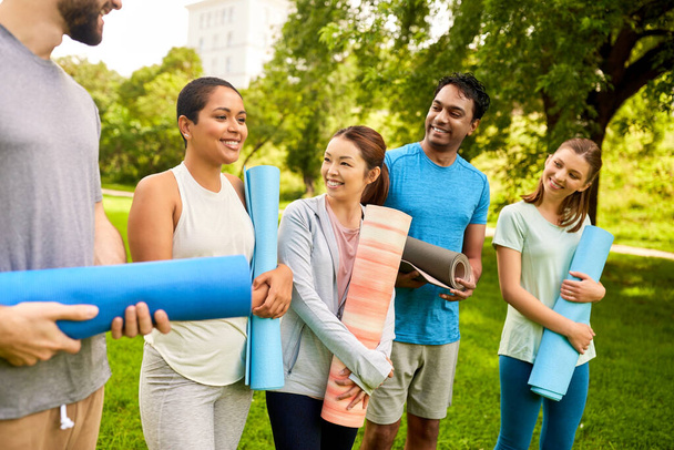group of happy people with yoga mats at park - Foto, Imagen