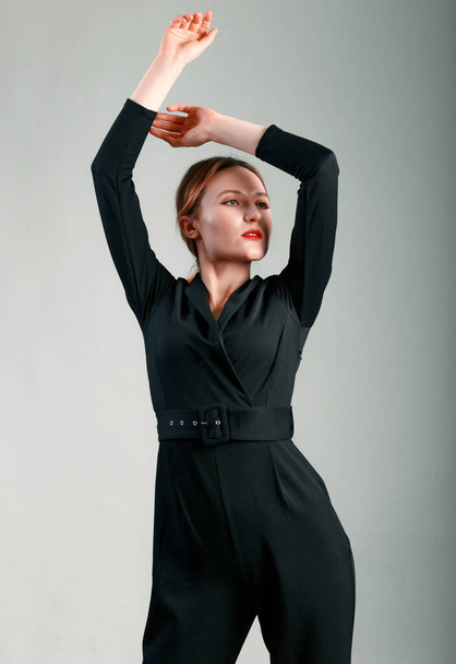 Элегантная деловая женщина в черном классическом комбинезоне позирует на сером фоне. - Фото, изображение