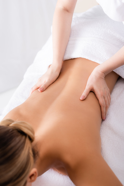 przycięty widok masażysty masaż pleców klienta leżącego na stole do masażu  - Zdjęcie, obraz