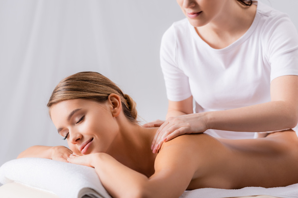 masajista mujer masaje complacido cliente acostado en mesa de masaje  - Foto, imagen
