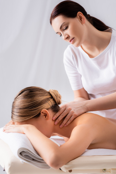 blurred masseur massaging neck of client lying on massage table  - Фото, зображення