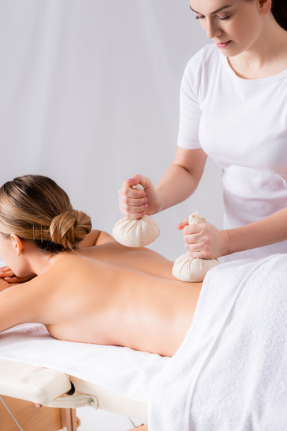 massaggiatore massaggiatore cliente con borse a base di erbe nel salone spa  - Foto, immagini