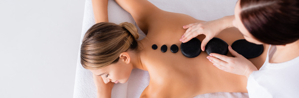 vista dall'alto della giovane donna ottenere massaggio con pietre calde nel salone spa, banner - Foto, immagini