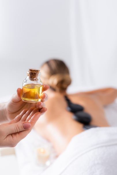 cropped view of masseur holding bottle with oil near client  - Foto, immagini
