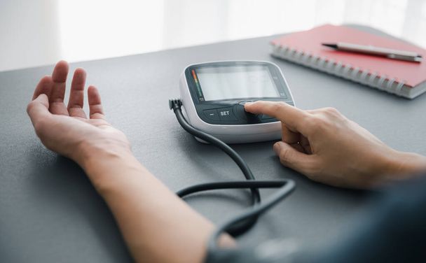 self blood pressure and heart rate measurement with blood pressure monitor machine, healthcare and medical concept - Photo, Image