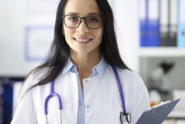 Портрет улыбающегося врача в очках в медицинском кабинете - Фото, изображение