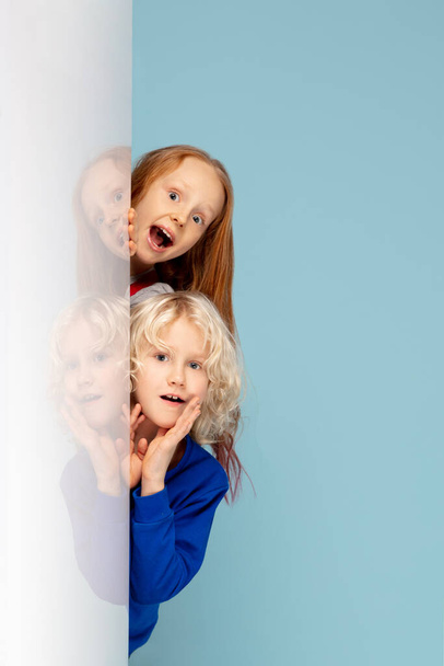 Happy children isolated on blue studio background. Look happy, cheerful, sincere. Copyspace. Childhood, education, emotions concept - Fotoğraf, Görsel