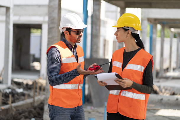 Инженеры мужского пола и женщины Фроманы носят защитные шлемы, проверяют подрядчиков и правильную прочность, строительные работы, домашнее строительство. - Фото, изображение
