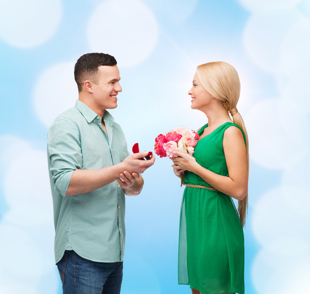 Smiling couple with flower bouquet and ring - Fotó, kép