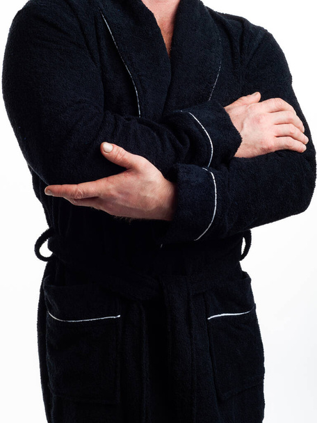 man in een helder, badjas adverteert kleding details op een geïsoleerde witte achtergrond. Genomen in de studio close-up. - Foto, afbeelding