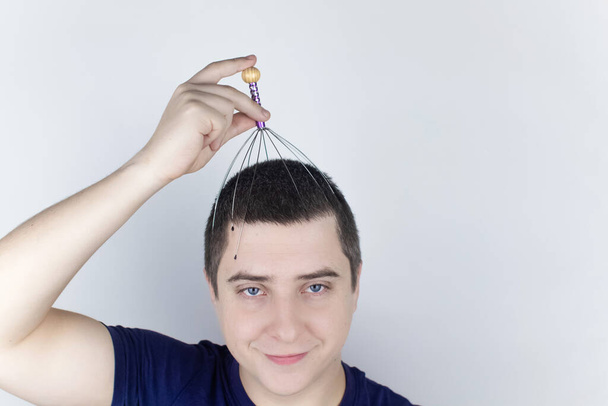 A man on a white background makes himself a head massage with a capillary massager. Self-help, anti-stress and relaxation concept - Photo, Image
