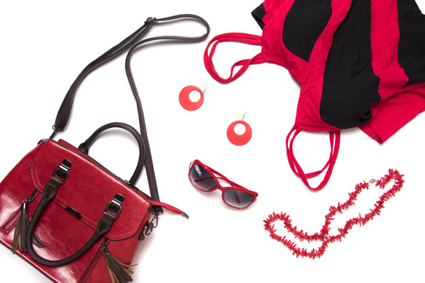 Top view or flat lay of female clothes and accessories collage, red women's handbag, glasses, blouse and necklace isolated on white background. - Foto, immagini