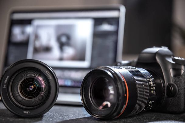 Professionelle Kamera und Objektiv in Nahaufnahme auf dem Desktop eines Fotografen auf einem unscharfen Hintergrund. Das Konzept der professionellen Ausrüstung für Foto und Video. - Foto, Bild