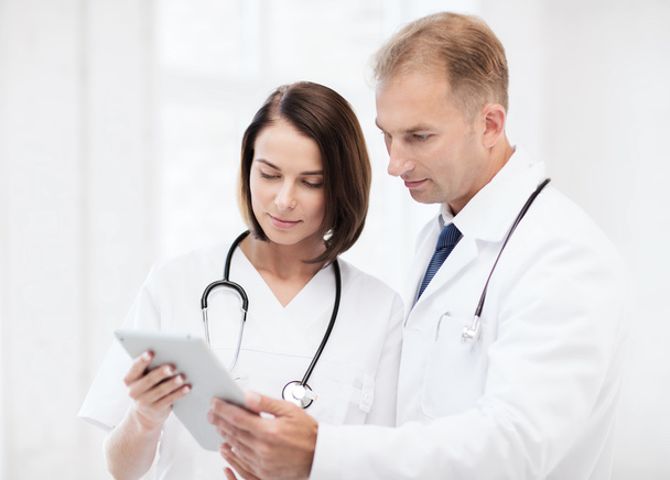 Two doctors looking at tablet pc - Fotó, kép