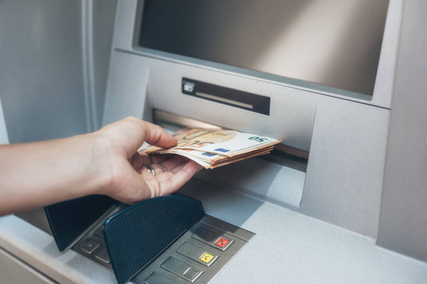Woman hand taking money from bank cash ATM machine. Close up. Cash point. Finance, transactions, credit card, money withdraw, currency concept - Foto, Bild