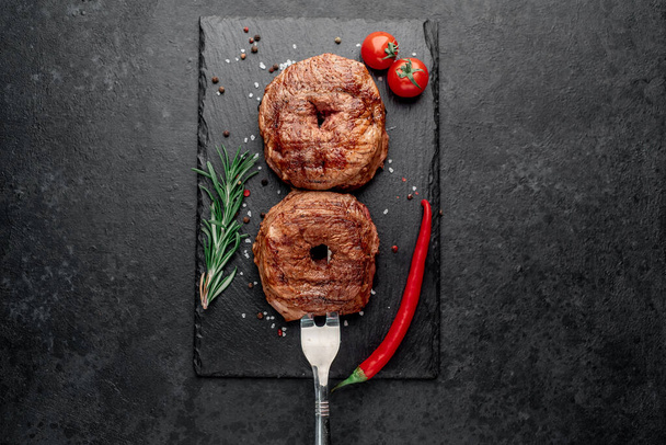 grillezett marhahús fűszerekkel és fűszernövényekkel sötét alapon - Fotó, kép