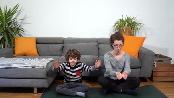 Onnellinen hauska ja hullu perhe asunnossa, äiti ja poika tekee jooga meditaatio kuntosali aikana Covid-19 Coronavirus lukitus karanteeni kotiin - elämäntapa olohuoneessa - Materiaali, video