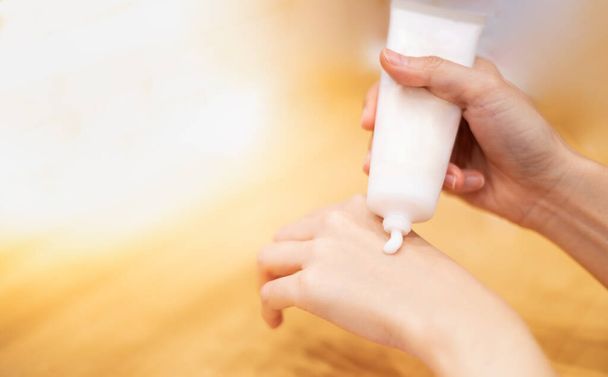 Close-up van vrouwelijke handen is het toepassen van hydraterende lotion crème voor een gezonde huid. Mooie vrouw is met behulp van vochtinbrengende veroudering behandeling op haar handen. - Foto, afbeelding