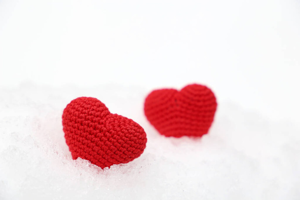 Valentine hearts in the snow. Two red knitted hearts in winter, symbol of romantic love, background for holiday - Foto, afbeelding