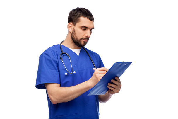 male doctor writing medical report on clipboard - Фото, зображення