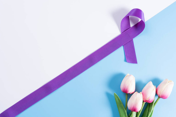 Dia mundial do câncer, fita roxa e flor de tulipa com fundo azul e com espaço de cópia para texto. Conceito médico e de saúde. - Foto, Imagem