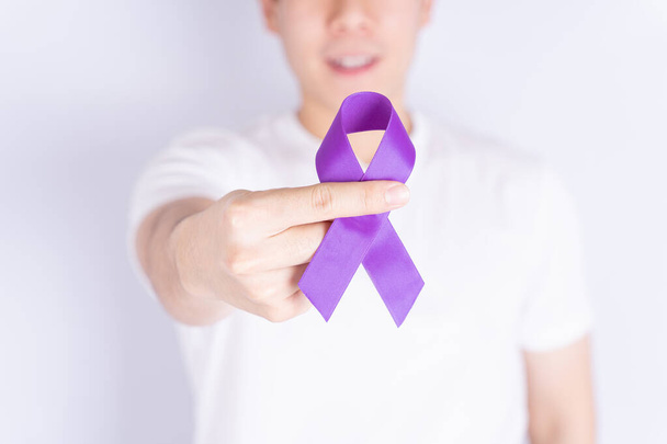 世界の癌の日、手はテキストのためのコピースペースと灰色の背景に紫色のリボンを保持。医療・医療の概念. - 写真・画像