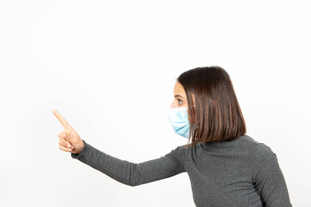 Mulher latina séria usando uma máscara cirúrgica comandando com autoridade. Cuidados de saúde durante o conceito de pandemia de Coronavirus. - Foto, Imagem