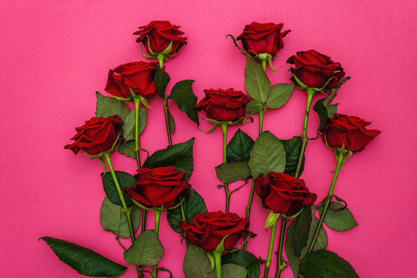 Friss burgundi rózsa csokor szív alakban, matt rózsaszín háttérrel. Illatos vörös virágok, ajándék koncepció Valentin-nap, esküvő vagy születésnap, felülnézet - Fotó, kép