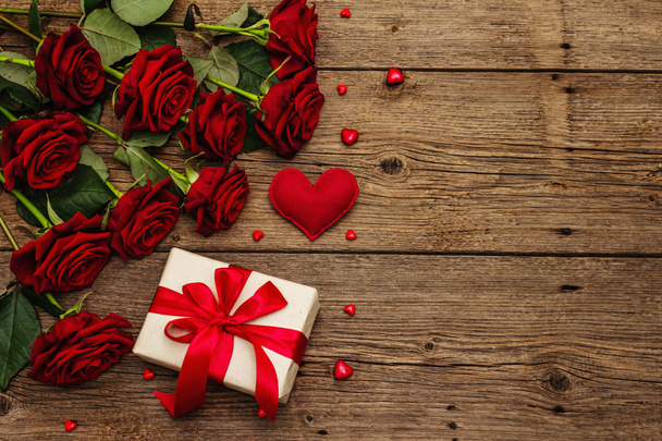 Valentýnské přání pozadí s dárkovými krabicemi, čerstvé burgundské růže a různorodé srdce. Klasický dřevěný stůl. Koncept svatby nebo narozenin, místo pro text, plochý ležel - Fotografie, Obrázek