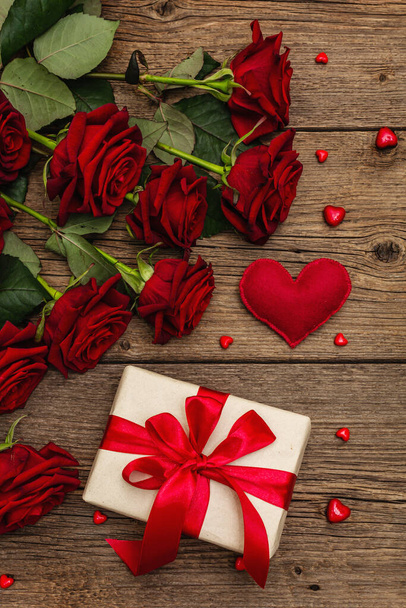 Valentine Grußkarte Hintergrund mit Geschenkboxen, frischen weinroten Rosen und sortierten Herzen. Vintage Holztisch vorhanden. Hochzeits- oder Geburtstagskonzept, Platz für Text, flache Lage - Foto, Bild