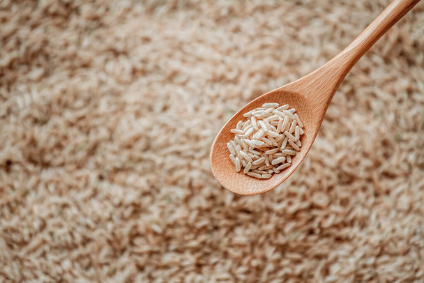 Brown rice in a wooden or bamboo spoon - Photo, Image