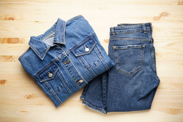 Jeans women's jacket and denim pants on the wooden background, top view. - 写真・画像