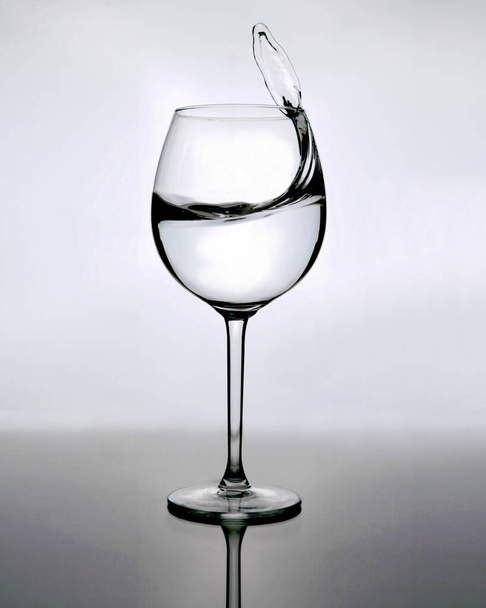 Acqua spruzzata nel bicchiere di vino sullo sfondo grigio - Foto, immagini