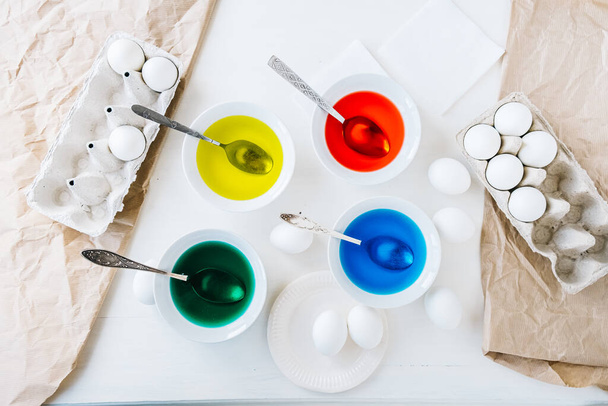 Pose plate Préparation de Pâques avec colorant alimentaire liquide. Différentes couleurs dans différents bols, egds sur fond blanc de table et de papier artisanal - Photo, image