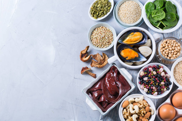 Healthy nutrition dieting concept. Assortment of foods high in iron. Beef liver, spinach, eggs, legumes, nuts, mushrooms, quinoa, sesame, pumpkin seeds, soy beans, seafood. Copy space, flat lay  - Photo, Image